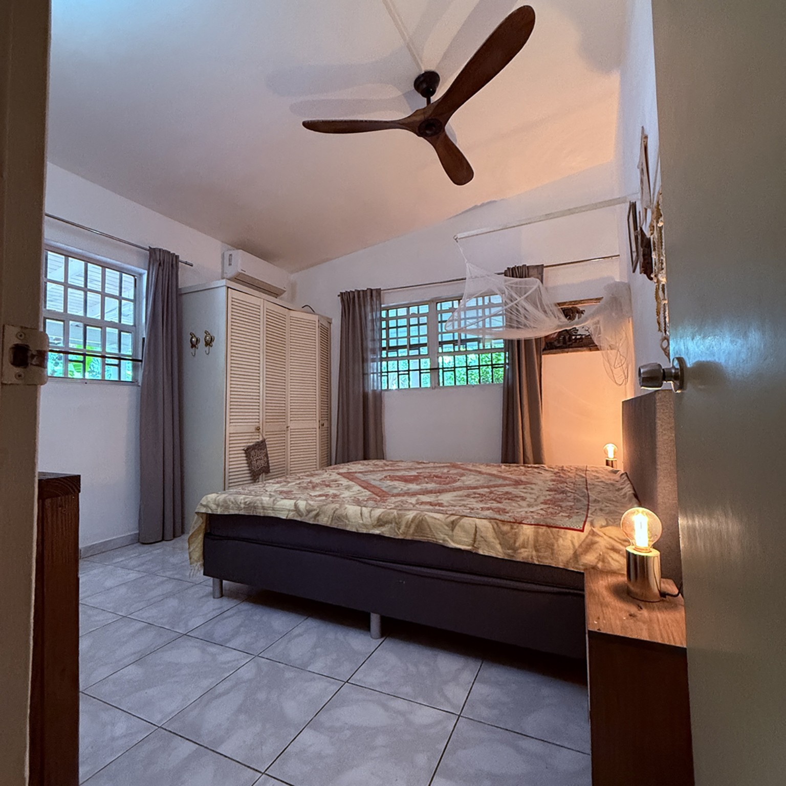 Eerste slaapkamer met airconditioning, plafondventilator en klamboe