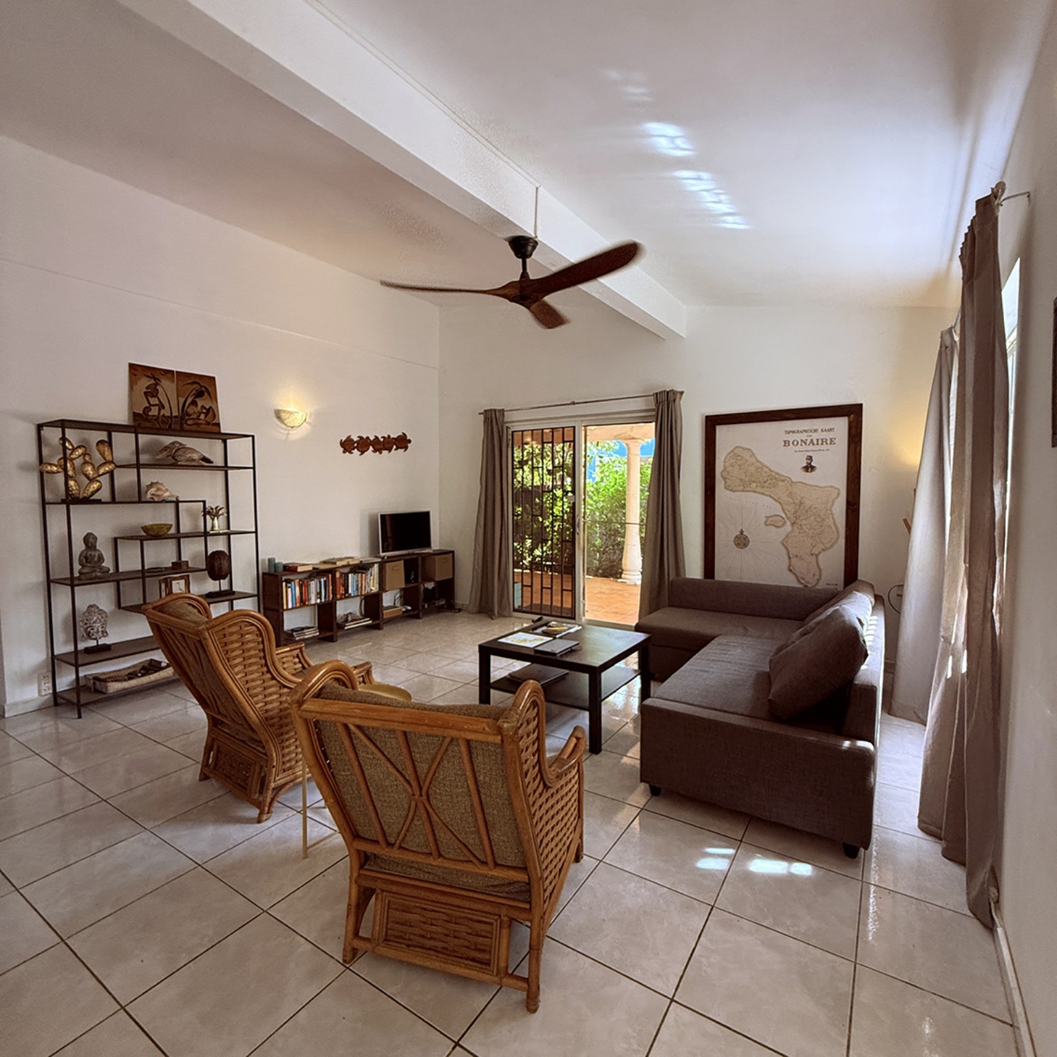 Ruime woonkamer met rotan stoelen en kaart van Bonaire